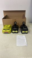 Photo showing the three battery chargers and an instruction sheet; one charger is green and appears used, two black with yellow Lithium-Ion batteries attached.