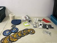 Overview of the lot including cutting discs, sanding wheels, grinder attachment, and other accessories spread on table.