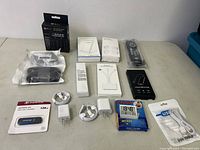 Photo showing entire lot of electronic accessories arranged on a table, including USB flash drive, chargers, cables, remote, and timer.