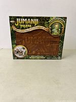 Front view of Jumanji Deluxe board game box with image of the electronic centerpiece and game title.