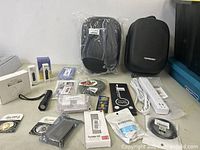 Overview of multiple new electronic items laid out on a table. Items include power strips, carrying cases, small electronic accessories and cables.