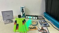 Photo showing floor light glowing green, neon green drumsticks, mini boom box, CDs, DVDs, drum tuner, and other music accessories.