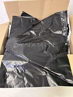 Black plastic bags with 'DYNAMITE' logo, in a cardboard box