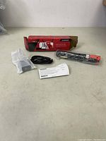 Full lot including Snap-on foldable dual pen light in plastic, USB charging cable, instruction sheet, and original box on a tabletop.