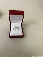 Infinity design 10K gold ring placed inside a red and white jewelry box.