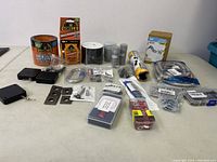 Overview of all lot items arranged on a table, showing tapes, hardware parts, screws, bolts, wire connectors, and small boxed items.