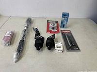 Overview of entire lot showing all tools and accessories arranged on table, including boxed Master Lock, Casoman socket set, gear puller, black adapters, and coiled tool.