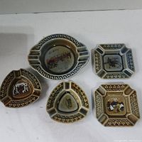 Top view showing five vintage ceramic ashtrays of different shapes and Irish decorative themes.