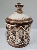 Front side of cookie jar showing embossed watermill building.