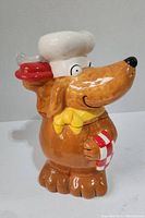 Front and side view of dog-shaped ceramic cookie jar with chef hat and scarf.
