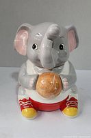 Front view of the elephant cookie jar showing facial features, basketball, and colorful shoes.