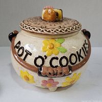 Front view of ceramic cookie jar labeled 'POT O' COOKIES' with floral and dog bone decorations.