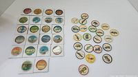 Scattered round and square Jello tokens including aircraft and travel images, showing condition and design variety.