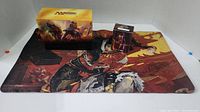 Magic The Gathering playmat and sleeved cards in deck box displayed on a white surface.