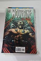 Front cover of Wolverine #26 showing Wolverine restrained by mechanical arms, horror expression, direct edition barcode visible.