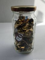 Glass jar full of assorted Olympic pins with metal lid labelled CLASSICO.