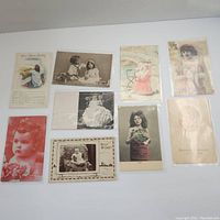 Full view of eight postcards laid out face up showing diverse vintage portraits and artistic images