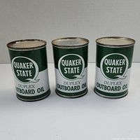 Front view of three Quaker State Duplex Outboard Oil cans showing branding and condition.