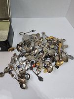 Photo showing a large pile of collectible souvenir spoons in various styles and sizes