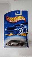 Black vintage styled Hot Wheels toy car in original blister packaging with blue backing card