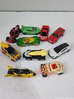 Ten assorted toy cars arranged on a white surface showing various angles and colors.