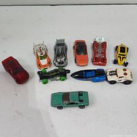 Image of 10 small toy cars arranged on a white surface, showing their variety in color and design.