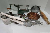 Front view showing the vintage apple peeler, potato ricer, rolling pin, copper mold, and other assorted kitchen tools.