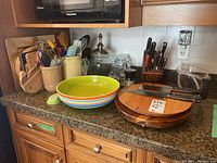 Full view of the kitchen counter showing wood butcher block, cutting boards, ceramic bowl, glass jars, knife block, and various utensils in containers.