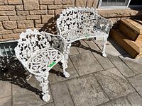 Bench and chair side by side outdoors on stone patio against brick wall