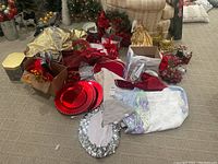 Lot of assorted Christmas decorations including plates, fabric decorations, floral pieces, and wreath in a basement setting