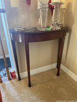 Front view of the wooden console table showing its curved edges and four straight legs.