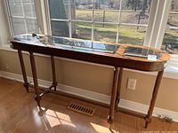 Full view of the wood console table alongside window showing overall shape, glass inserts, and condition of wood finish.