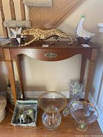 Front view showing all decorative glass and resin/plaster animal figures arranged on and beneath a wooden console table.