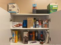 Cabinet shelves with various cleaning products, sprays, disposable wipes, and other household supplies.