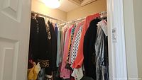 Wide view of rack with assorted ladies clothing including sweaters, blazers, and shirts in various colors and styles.