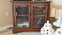 Front view of wood media cabinet with beveled glass doors and metal knob handles.
