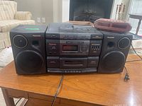 Panasonic RX-DS750 portable stereo system with dual speakers and Beaumark AM/FM clock radio on wooden surface