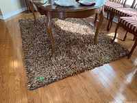 Rug under a wooden table with chairs, showing full length and pile texture.