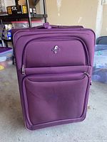 Front view of large purple rolling suitcase with Atlantic logo and multiple zippered compartments