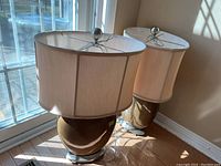 Pair of matching table lamps with ceramic bases and fabric shades positioned near window light