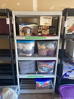 Full view of plastic utility shelf with multiple bins and boxes placed on shelves.