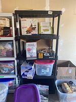Front view of black plastic modular utility shelf showing all four shelves and empty space on each level.
