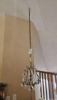 Full view of the vintage brass chandelier hanging from a chain, showing the entire fixture including chain and swag hanger.