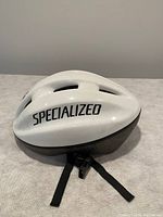 White Specialized adult bike helmet displayed from side angle showing brand name, ventilation, and straps.
