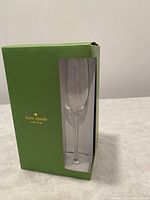 One of four green Kate Spade New York branded boxes with a champagne flute inside, showing the flute and packaging intact and new.