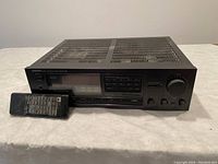 Onkyo TX-DS474 stereo receiver with remote control placed on a white surface against a plain background. Front view showing buttons, tuning dial, and remote details clearly.