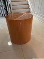 Round wooden side table with polished top and smooth finish.