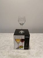 Photo of a single clear wine glass placed on top of the box showing the brand and package information.