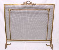 Full view of the brass fireplace screen showing the mesh center, brass frame, and cast brass feet and handle