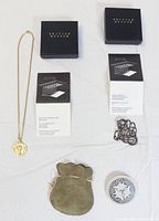 Three British Museum jewelry items displayed: gold plated Roman coin necklace with chain, bronzed Viking metal brooch, blue and white ceramic Celtic rabbit brooch with leather pouch. Two black British Museum boxes and museum documentation cards present.